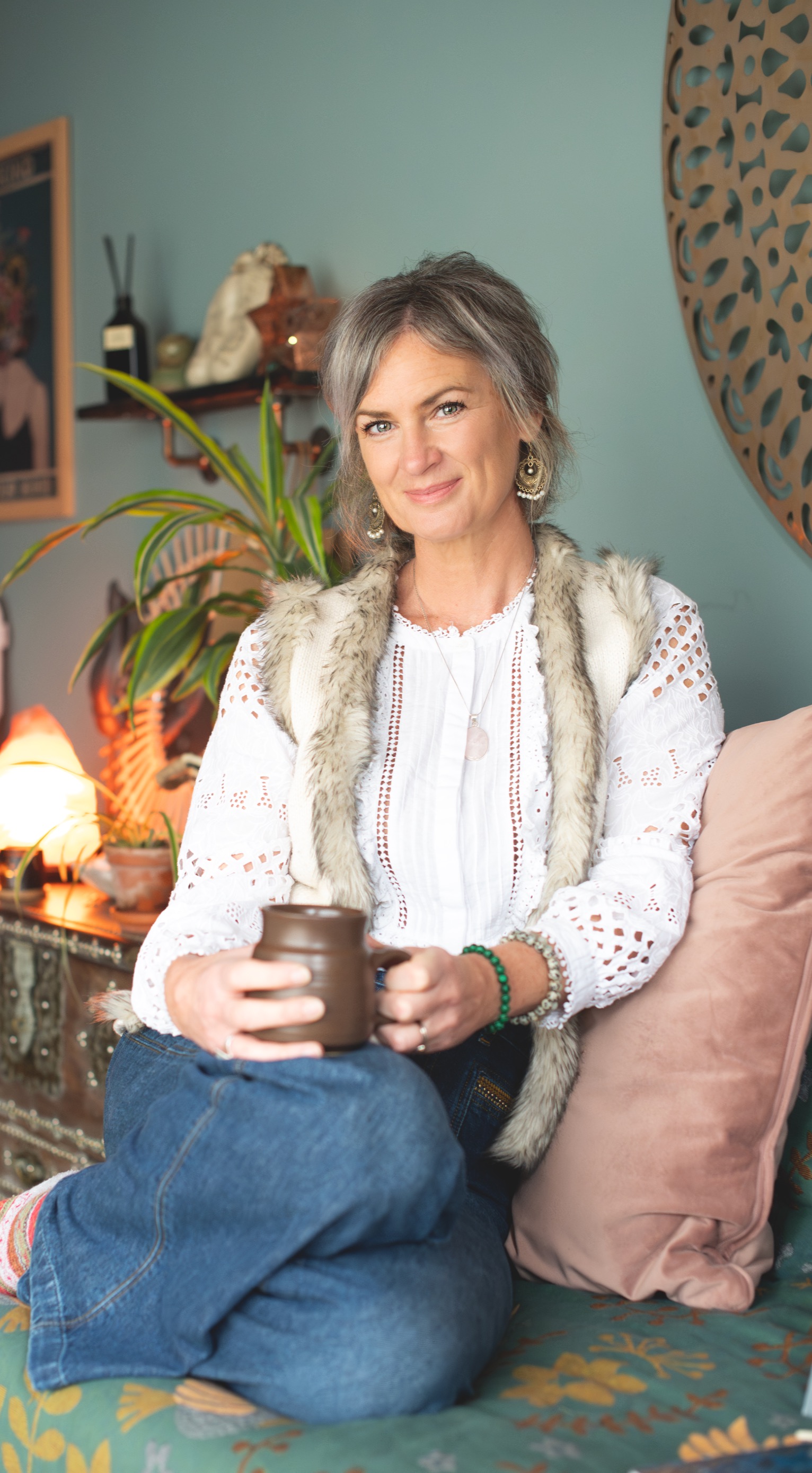 Suzannah seated with a mug in her Nurture Nest treatment space
